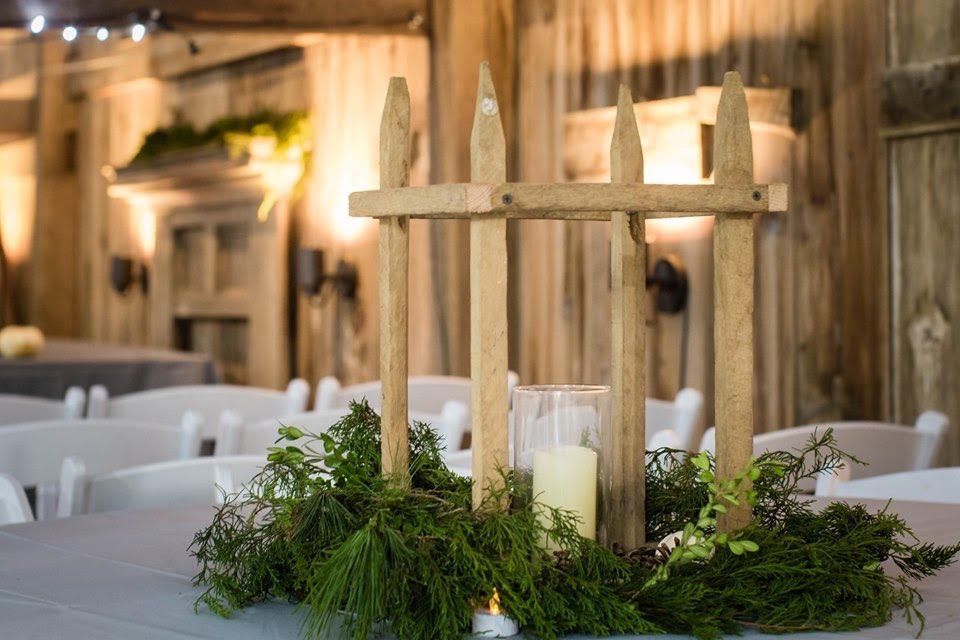 A rustic picket-fence centerpiece with evergreens and a candle